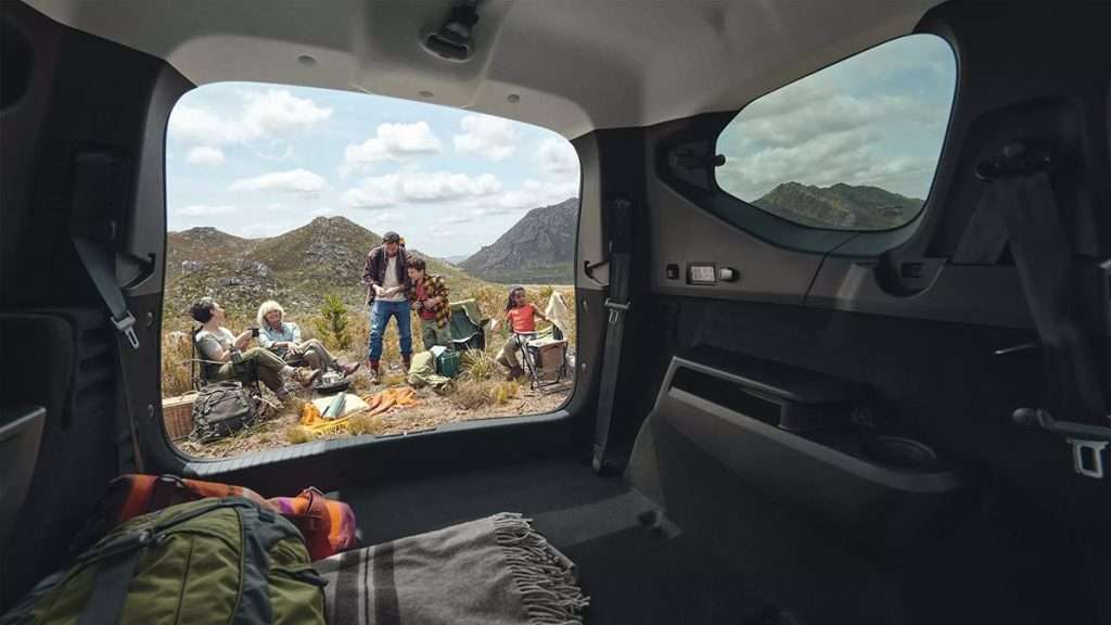 Blick aus dem Kofferraum eines Dacia Jogger auf eine Familie beim Camping