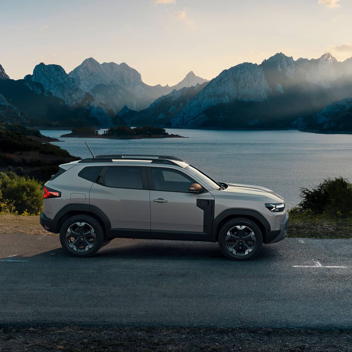 Dacia Duster in der Seitenansicht auf einer Straße vor Gebirgssee