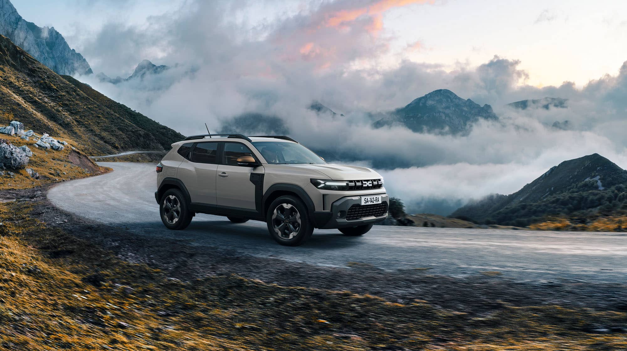 Dacia Duster auf Gebirgsstraße vor tiefliegenden Wolken