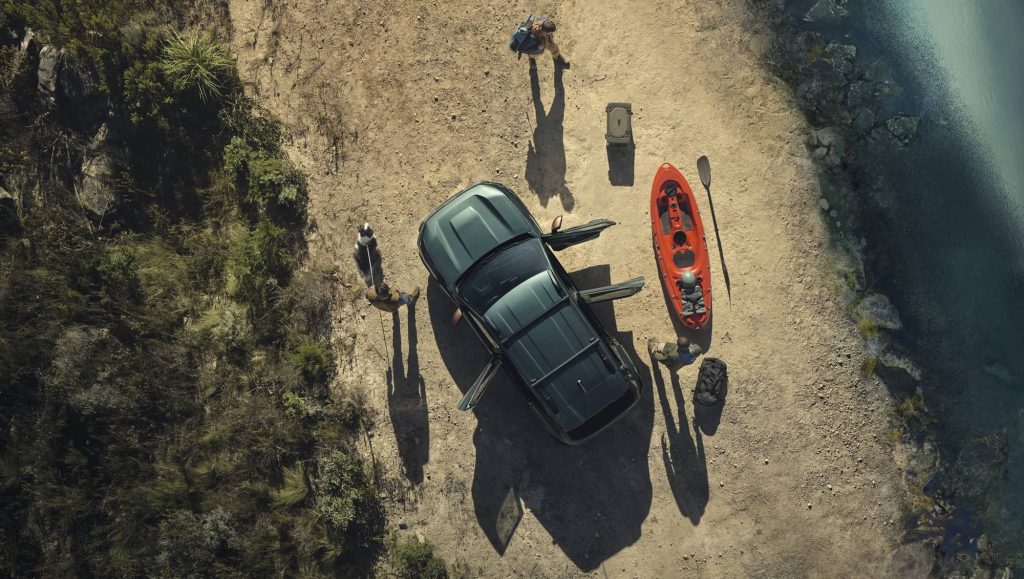Grüner Dacia wird am Strand ausgeladen mit Kayak am Strand