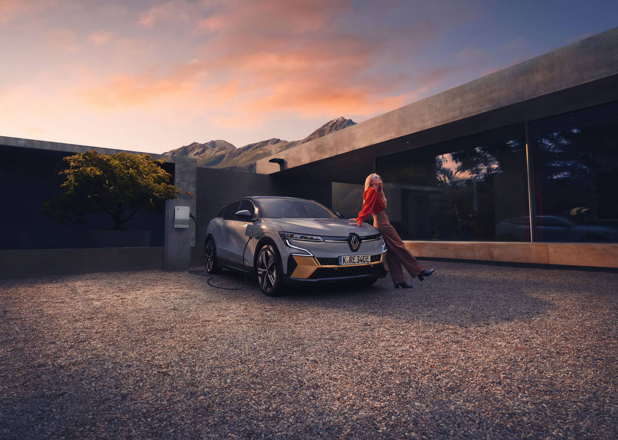 Renault Megane an der Wallbox, eine Frau sitzt auf der Motorhaube