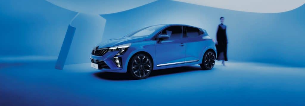 Renault Clio in blau mit einer Frau im Hintergrund