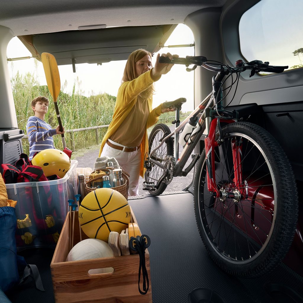 Renault Trafic Combi Sicht aus Kofferraum auf Familie die Sportgeräte einlädt