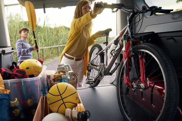 Renault Trafic Combi Sicht aus Kofferraum auf Familie die Sportgeräte einlädt