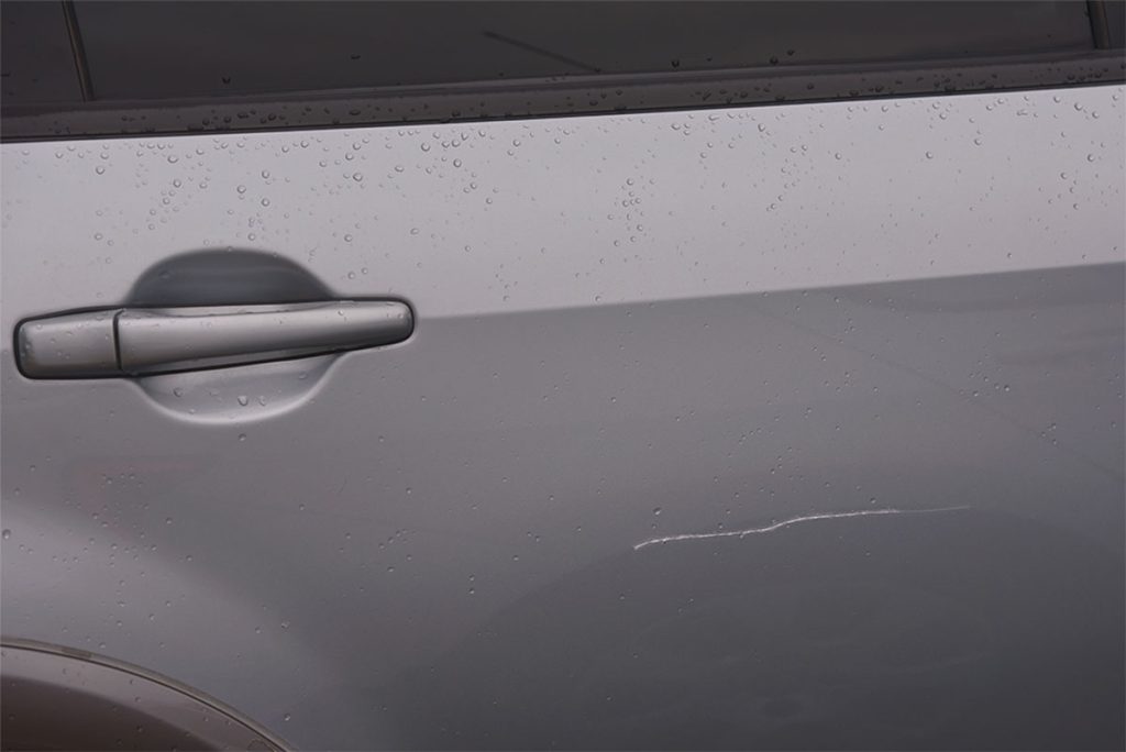 Kratzer im Lack in der Seitentür eines grauen Fahrzeugs