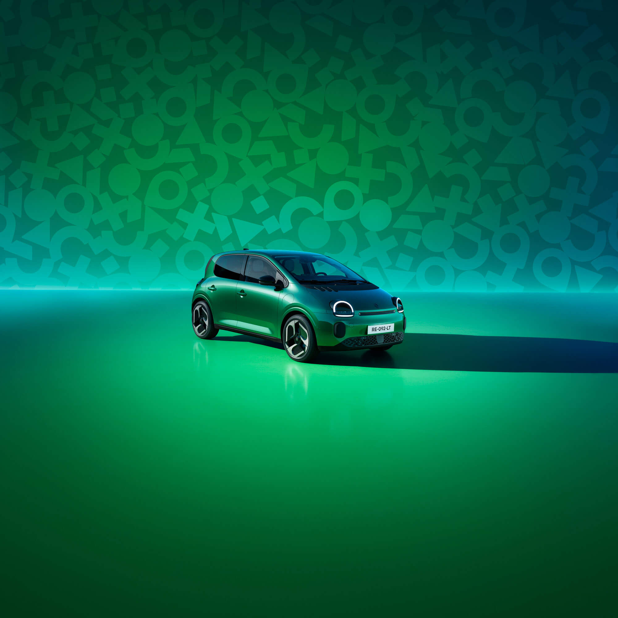 Renault Twingo Schrägansicht auf die Front vor grüner Wand mit Twingo Symbolen